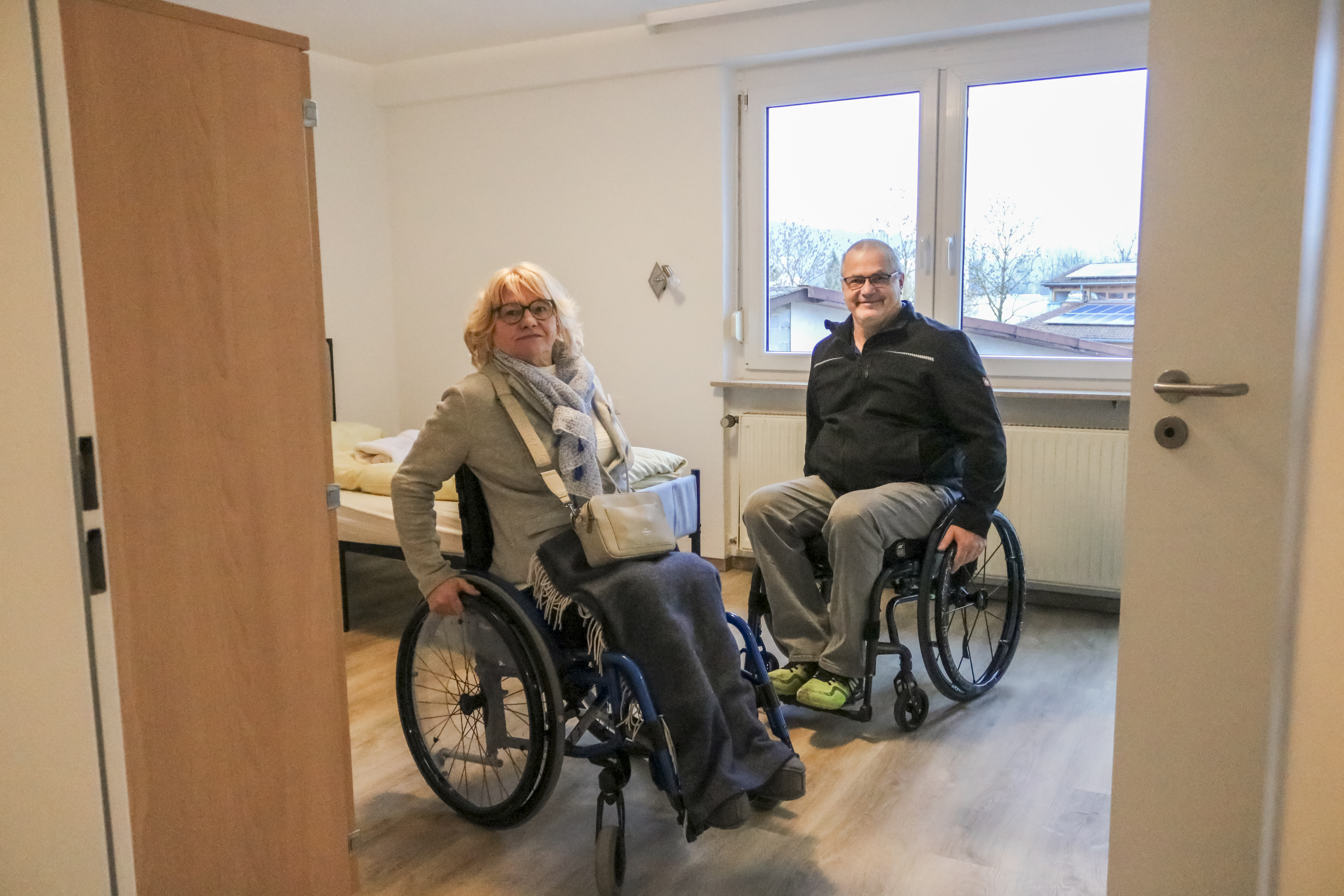 Zwei Rollstuhlfahrende inspizieren ein Zimmer