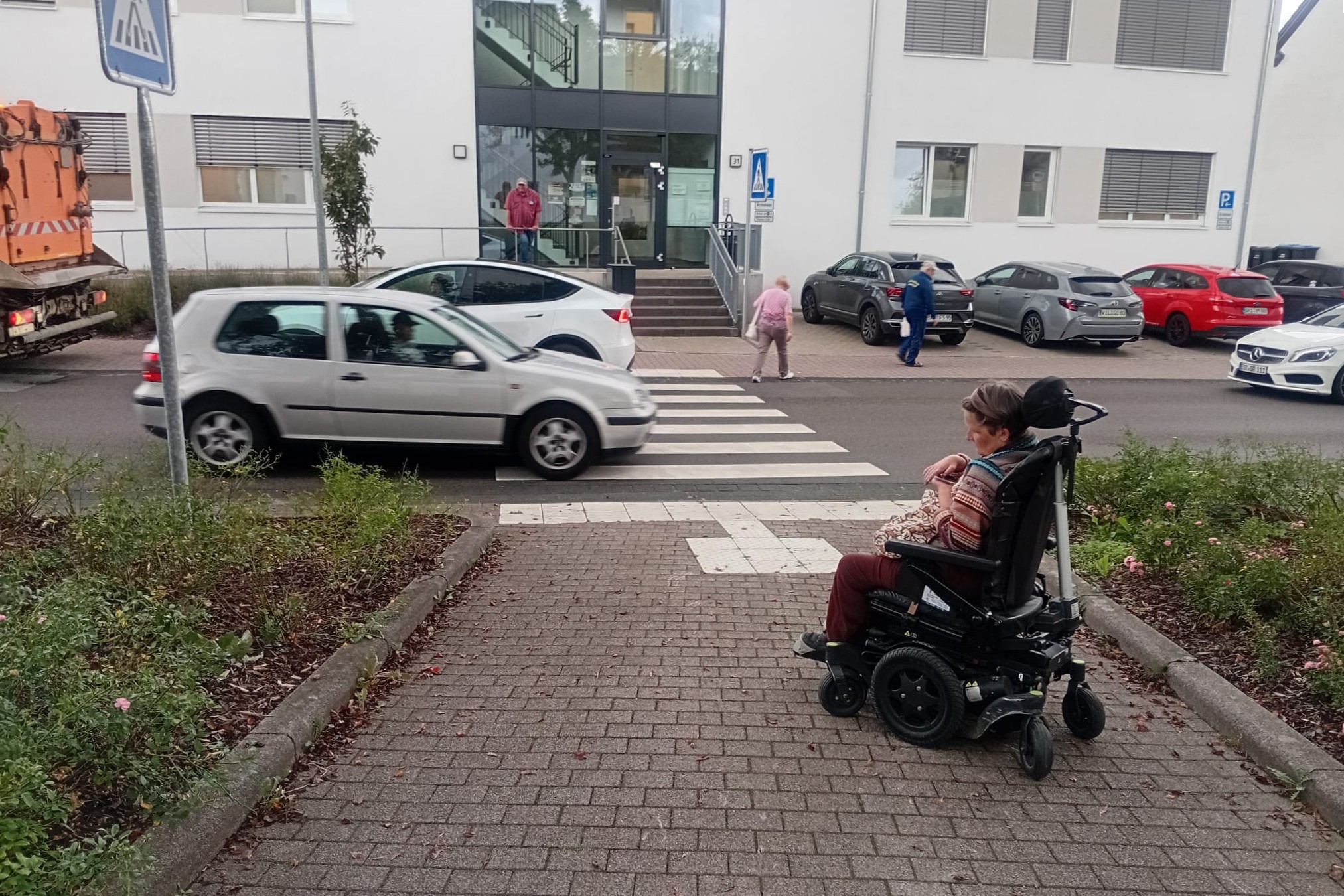 E-Rollstuhlfahrende vor einem Straßenübergang