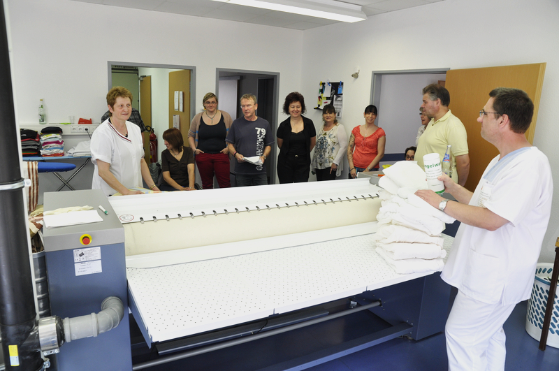 Menschen um einen Tisch, der Ausbilder erklärt etwas.