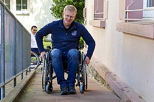 Andreas Insam (Bürgermeister von Krautheim) fährt im Rollstuhl eine Rampe hoch