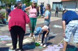 Menschen (Erwachsene und Kinder) malen auf einer Straße