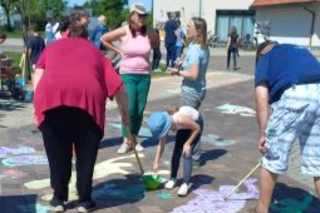 Menschen (Erwachsene und Kinder) malen auf einer Straße