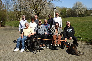 Man sieht eine Gruppe von 10 Personen. 5 davon sitzen im Rollstuhl. Zudem sind zwei schwarze mittelgroße Hunde im Bild. Es handelt sich um die Teilnehmenden an der BSK-Schulung „Digitalisierung im Gesundheitswesen“ in Duderstadt. 