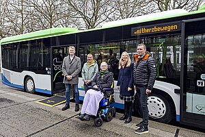Fünf Menschen mit und ohne Behinderung vor einem Niederflurbus mit ausgeklappter Rampe