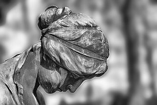 erwachsene Engelskulptur - gesenkter Kopf - auf einem Friedhof