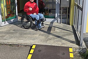 Mirko Herrmann in seinem Rollstuhl auf der Stufe des barrierefreien Wahllokals, davor eine Rampe.