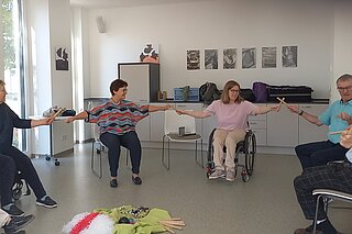 Menschen im Rollstuhl und auf Stühlen beim Sitztanz