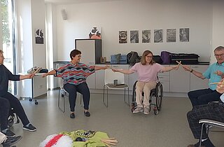 Menschen im Rollstuhl und auf Stühlen beim Sitztanz
