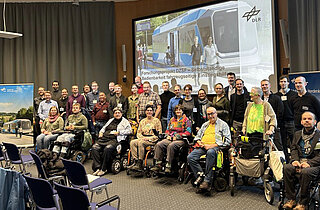 Gruppenfoto der Teilnehmenden und des Moderatoren-Teams beim Workshop "Selbstständige Bedienbarkeit fahrzeugseitiger Einstiegshilfen" in Berlin-Adlershof