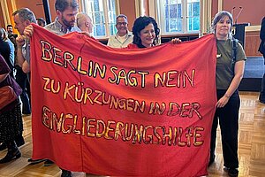 Jörg Bechtold und Senatorin Kiziltepe und noch jemand halten ein Banner hoch:  Berlin sagt nein zu Kürzungen in der Eingliederungshilfe