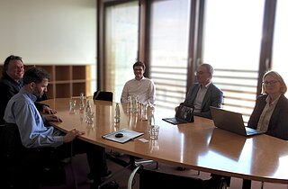 Fünf Menschen sitzen an einem Tisch.