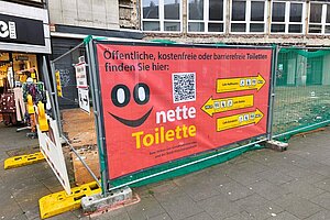 nette Toilette Plakat am Bauzaun