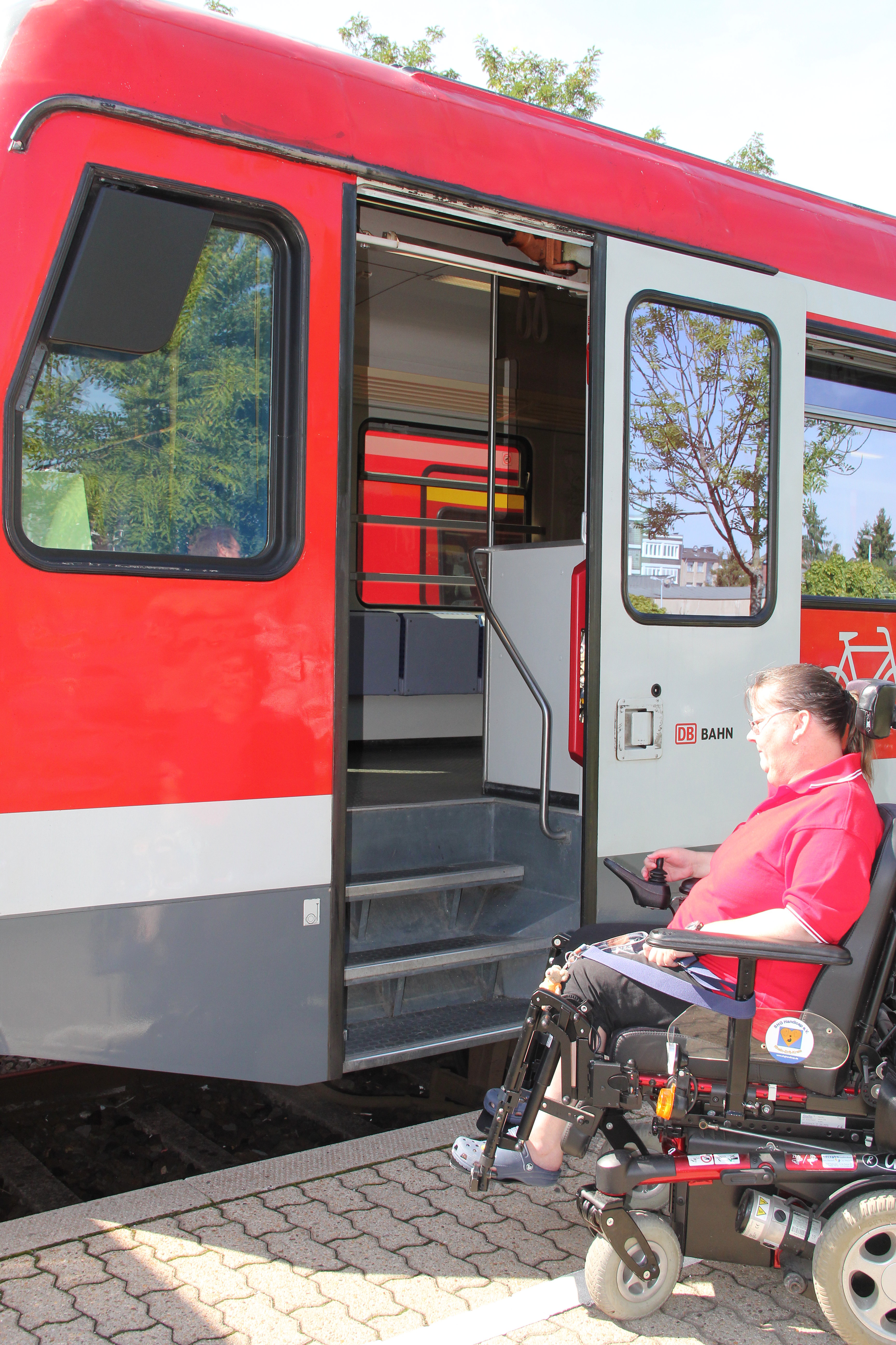 Rollstuhlfahrerin vor Treppen am Eingang der S-Bahn 