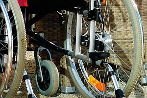 Die Räder eines Rollstuhls von hinten mit Stützrädern