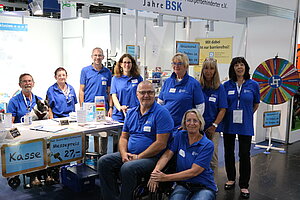 Das Foto zweigt neun Personen in blauen BSK-Shirts an einem Messestand. Es handelt sich um das Team aus Haupt- udn Ehrenamtlichen des Bundesverbands, das vier Tage auf der RehaCare-Messe in Düsseldorf im Einsatz war.